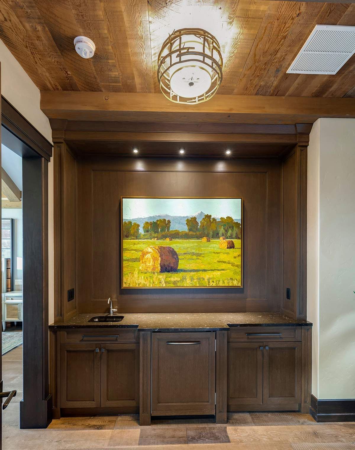 A kitchen with a painting on the wall above a sink.