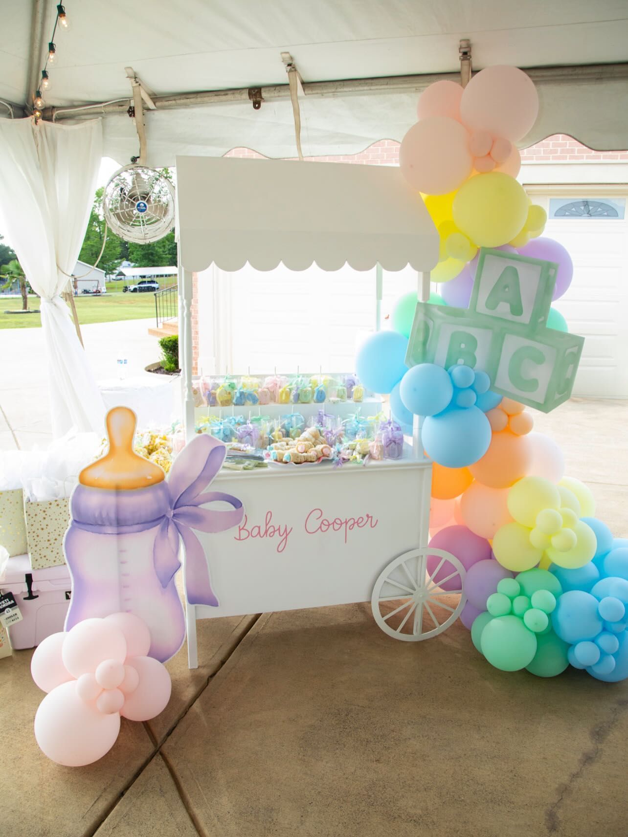 Baby shower candy cart decorated with pastel balloons and decorations.
