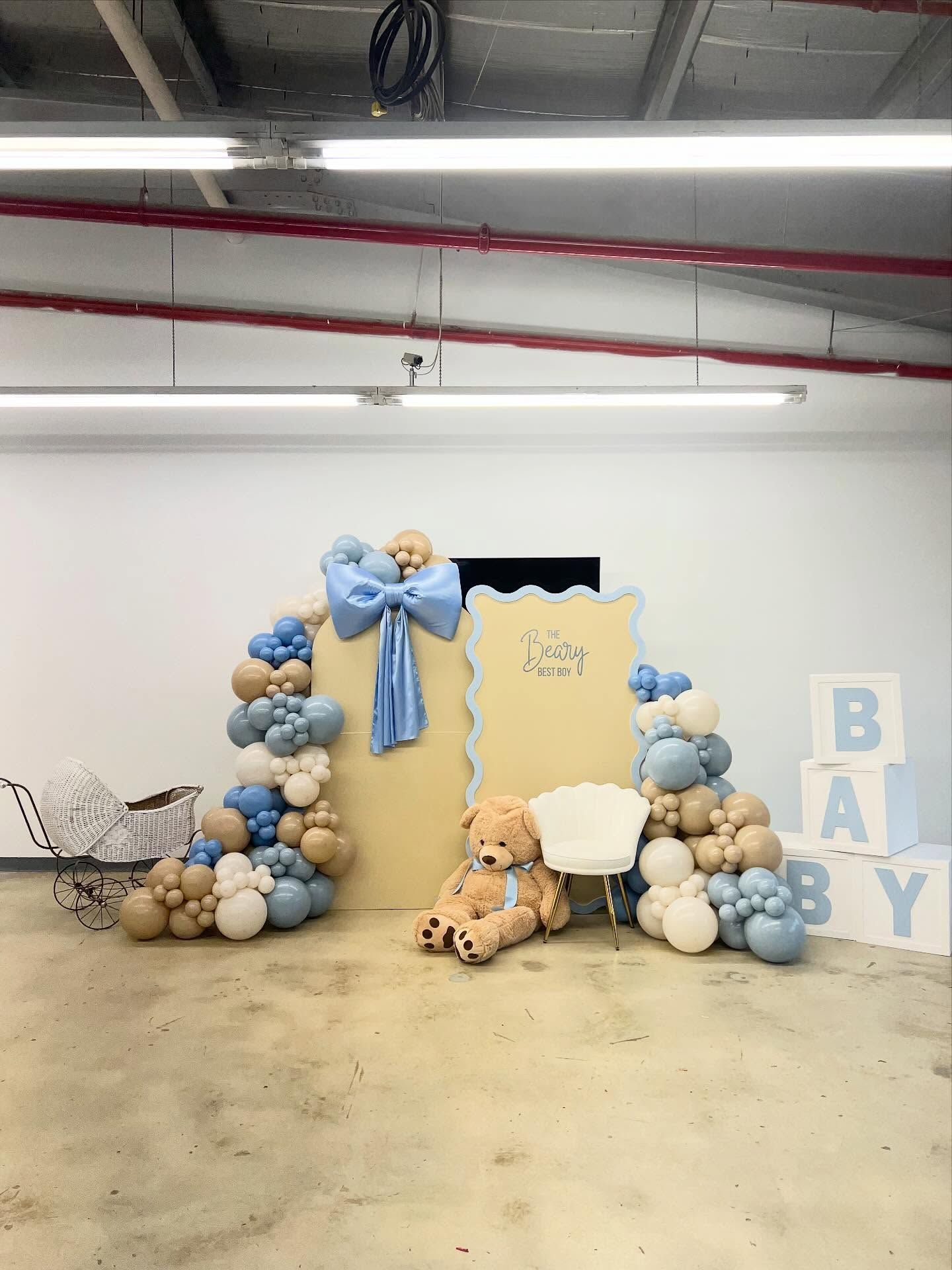 Baby shower setup with blue, beige balloons, teddy bears, 