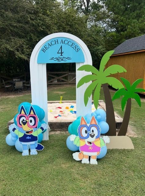 Superhero Bluey and Bingo cutouts by a beach-themed play area.