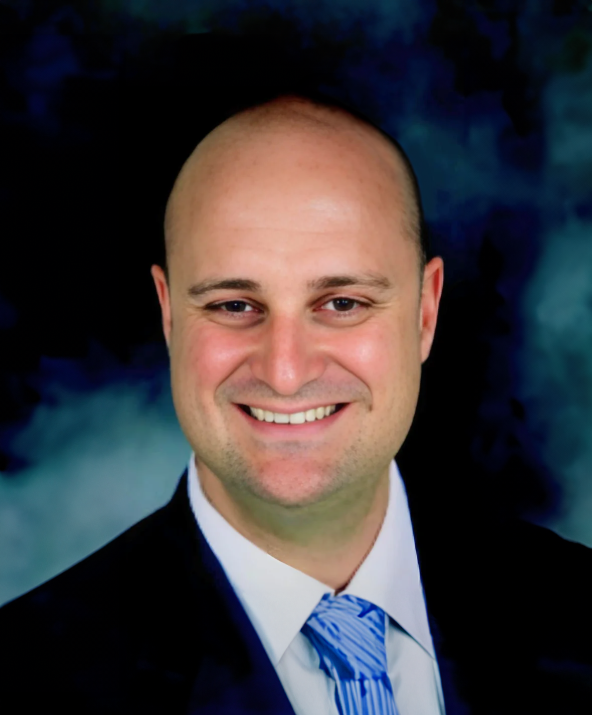 A man with a beard wearing a blue suit and red tie