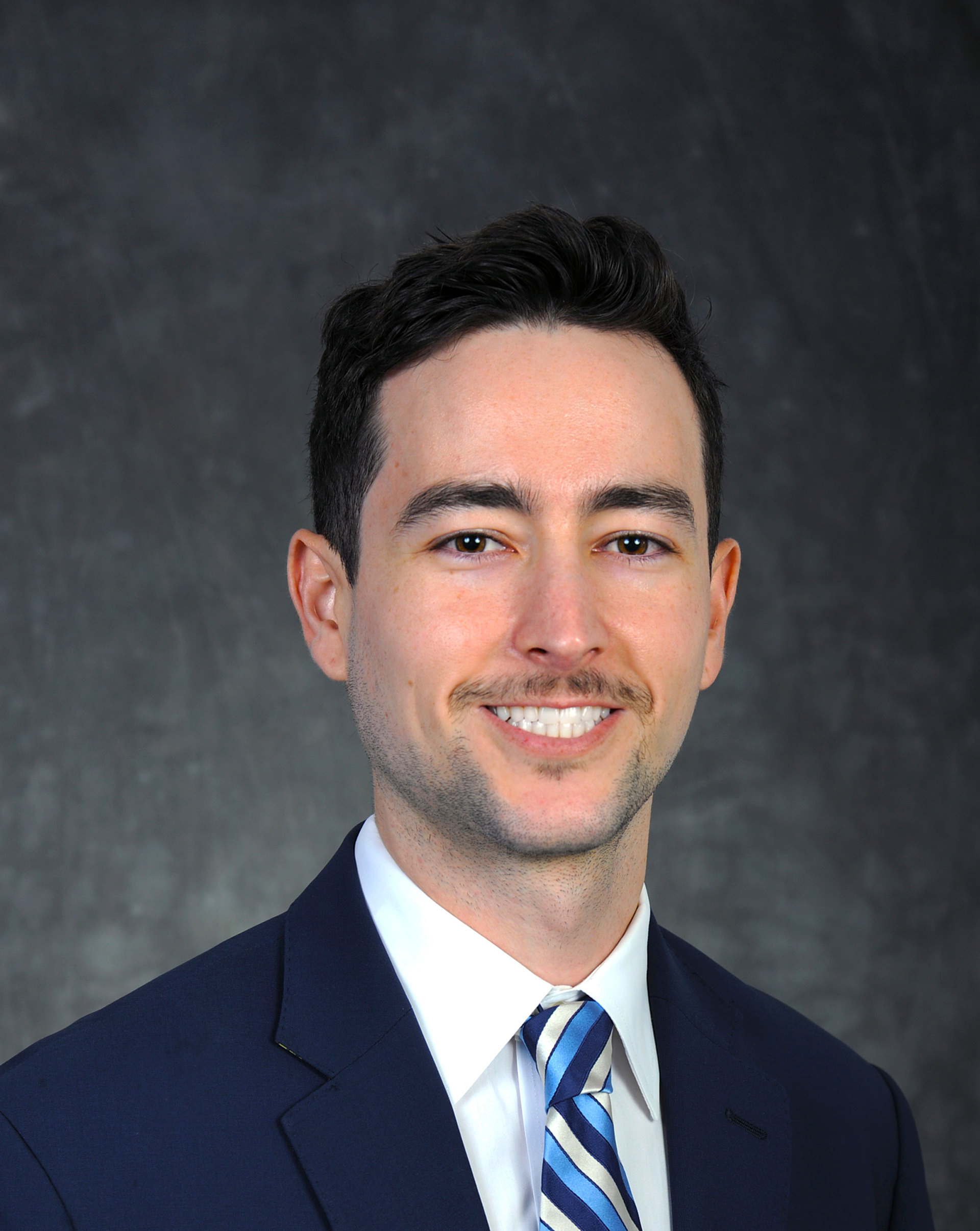 A man with a beard wearing a blue suit and red tie