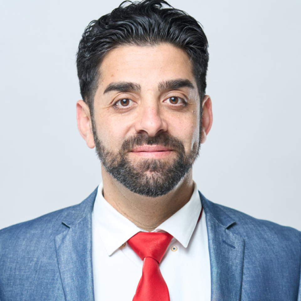 A man with a beard wearing a blue suit and red tie