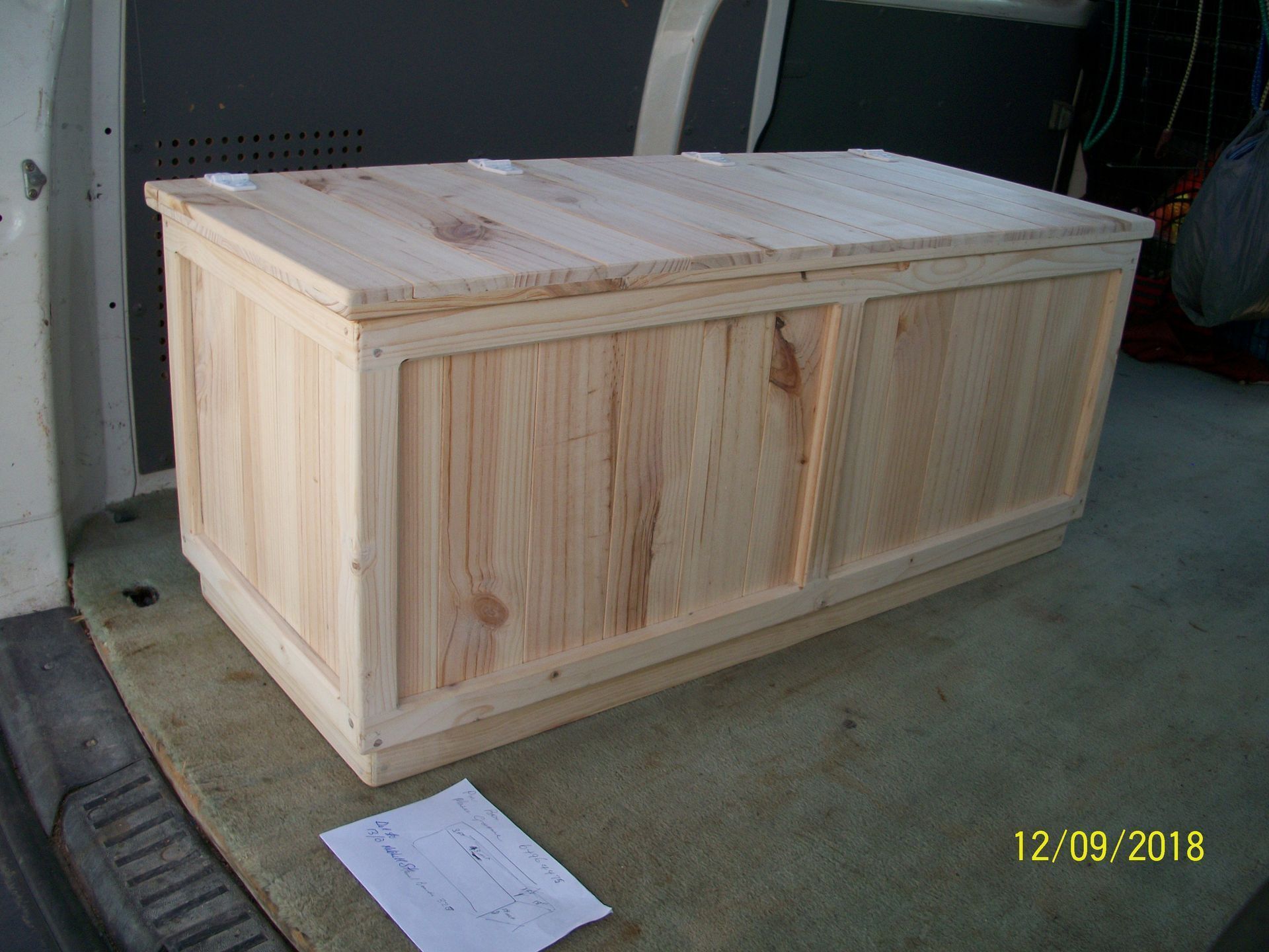 Light wood crate in a garage, sitting on concrete floor.