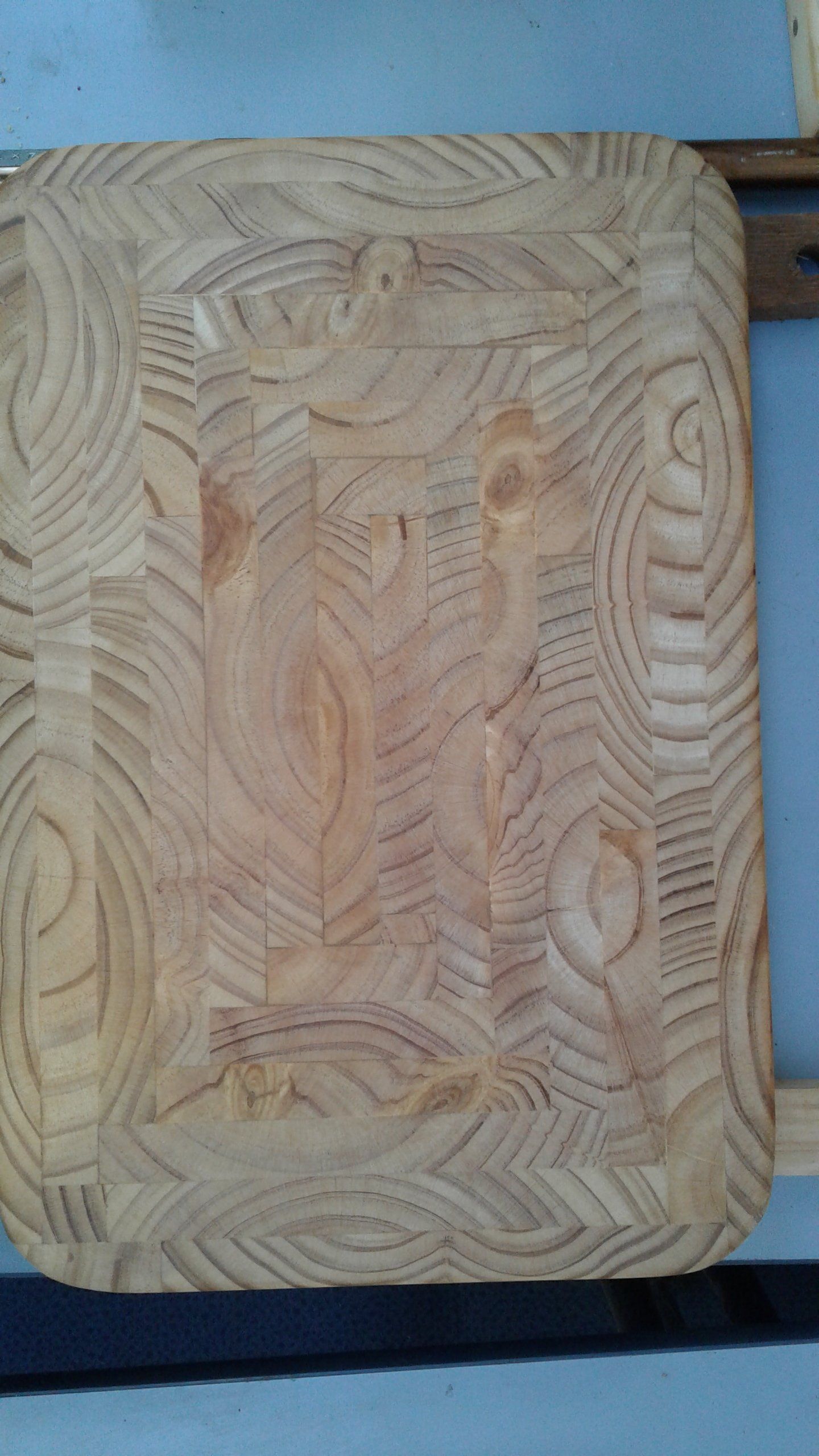 Close-up of a light wood rectangular cutting board with carved leaf-like patterns