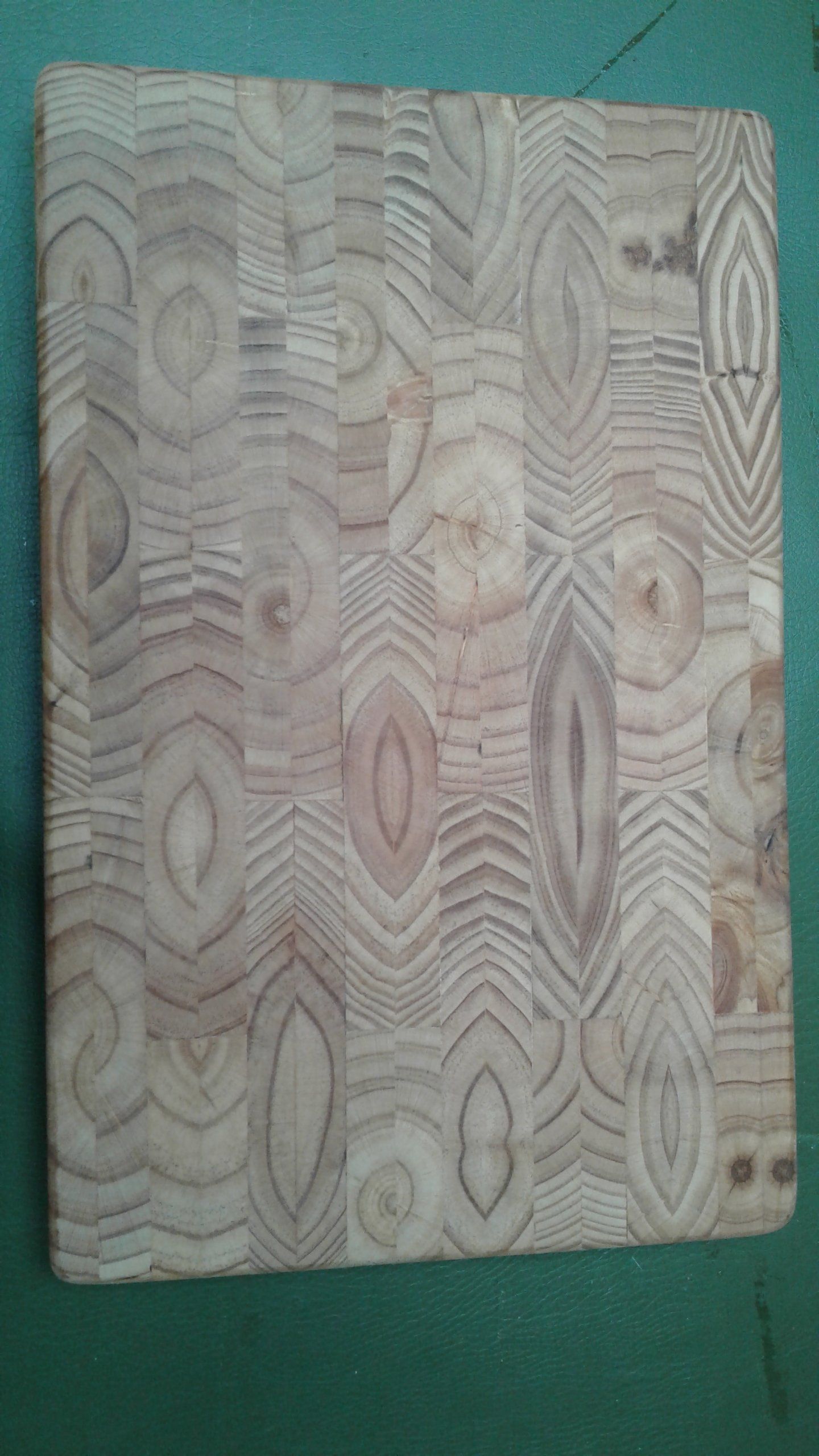 Rectangular wood-grain panel with light beige and pink tones on a green background