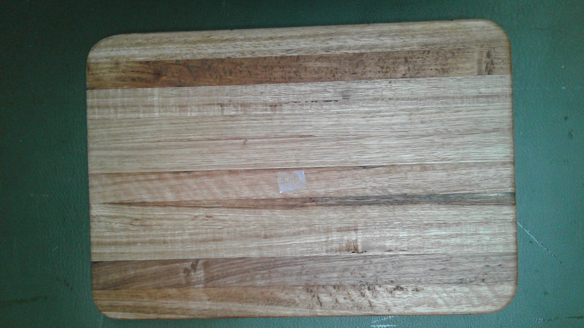 Small rectangular wooden cutting board with rounded corners on a green surface