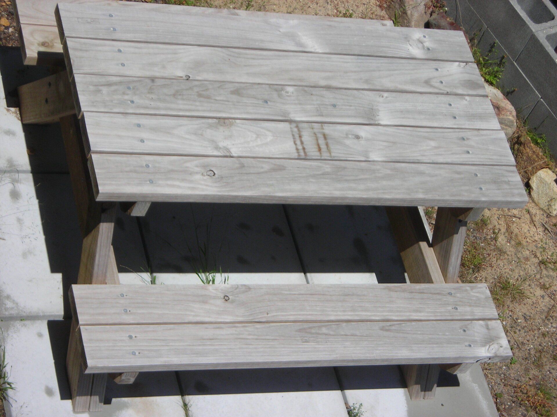 Weathered wooden steps with a handrail, viewed from above outdoors.