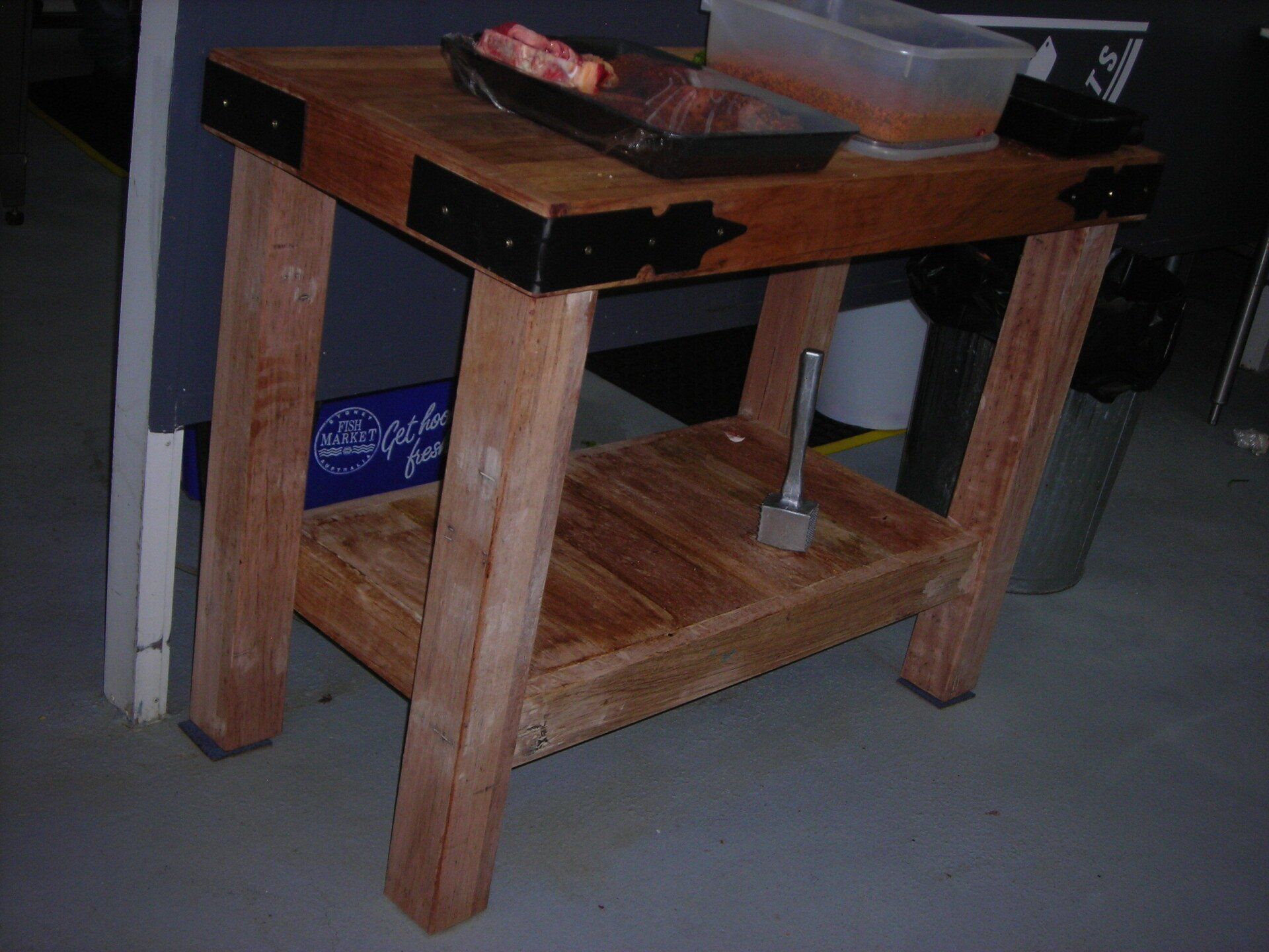 Small wooden workbench with a dark top and lower shelf in a workshop setting