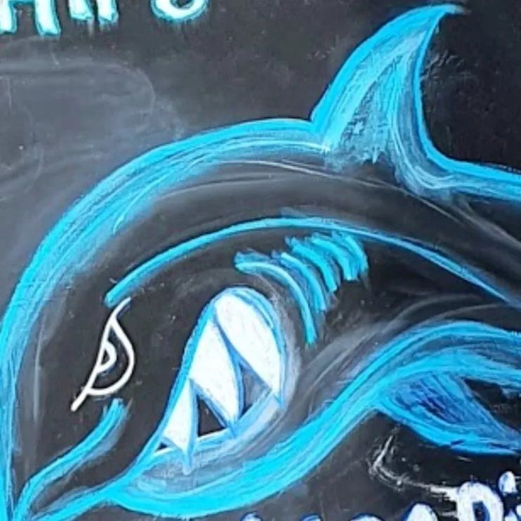 Blue neon-style shark graffiti on a dark wall, showing a side profile with an open mouth.