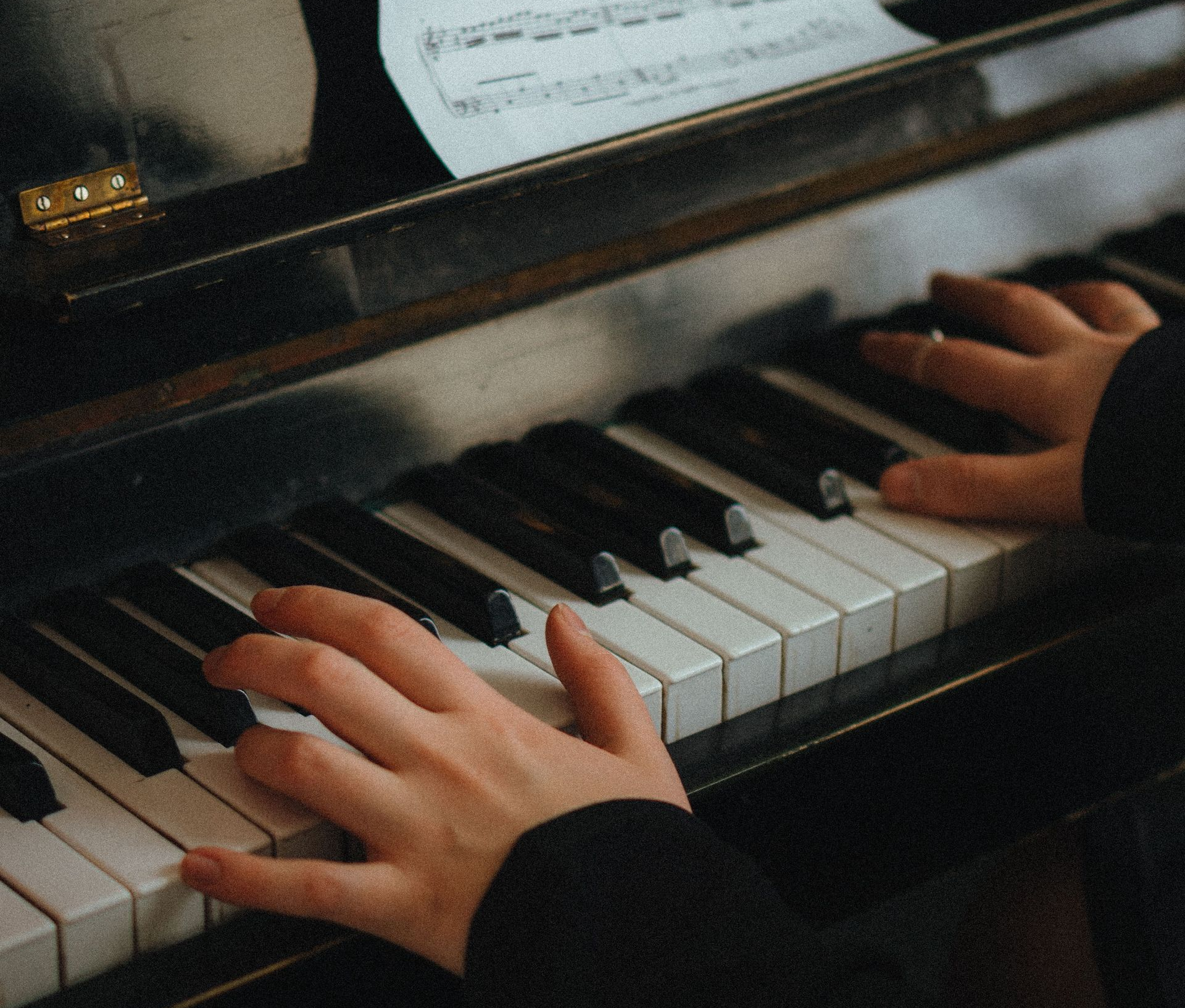 Hands playing a piano keyboard close-up.