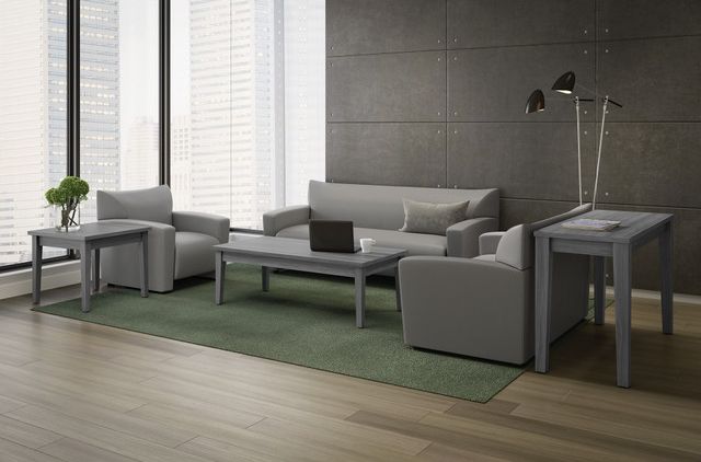 Gray office waiting area with sofa, chairs, tables, and green rug.