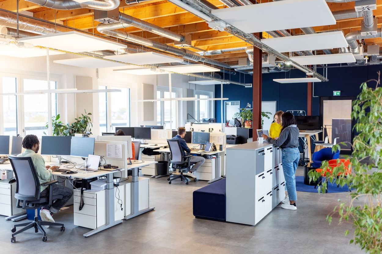 Modern office with people working, plants, and natural light.