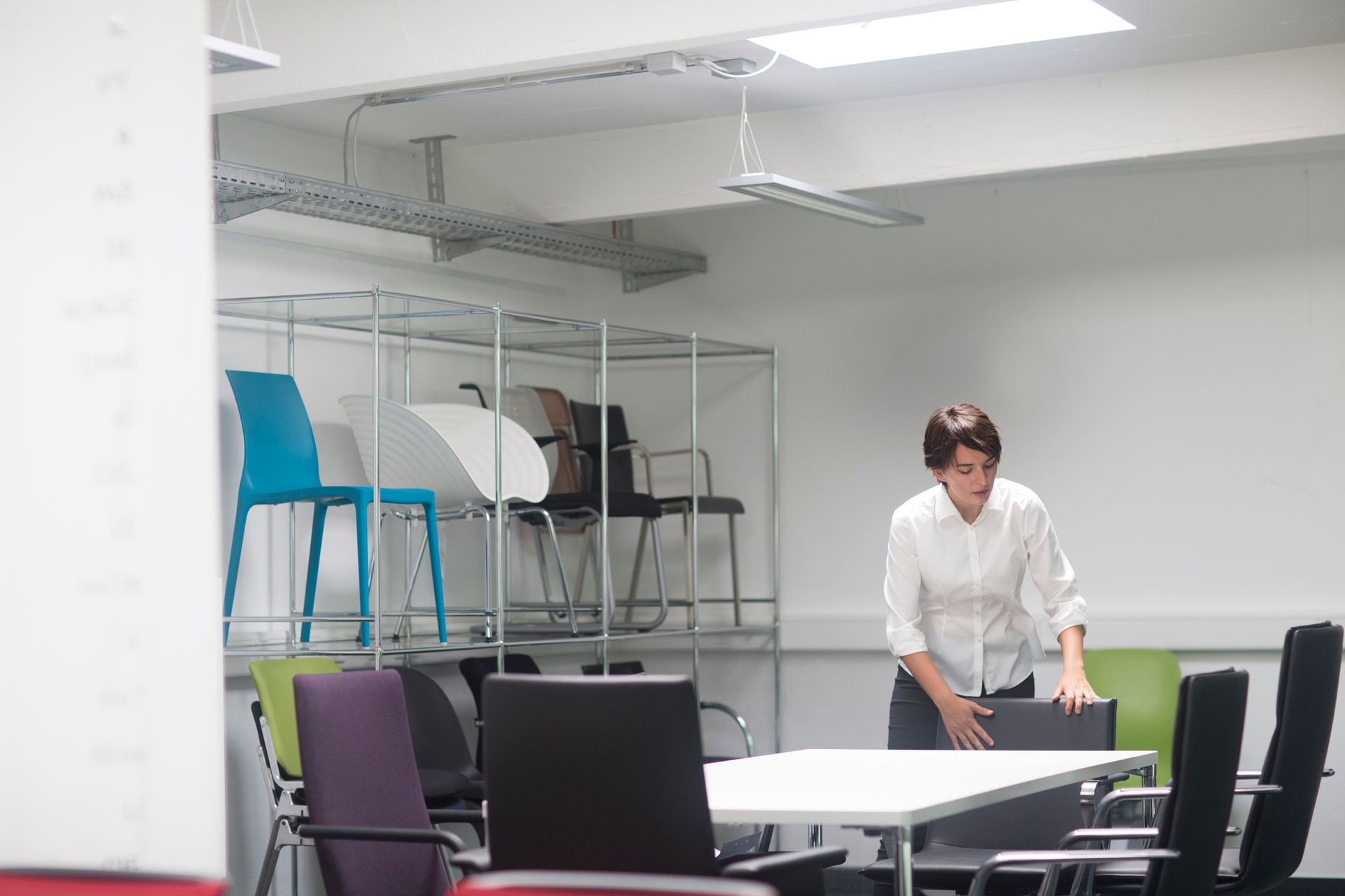 Young female sales manager organizing chairs in office furniture store. Young female sales manager organizing chairs in office furniture store.