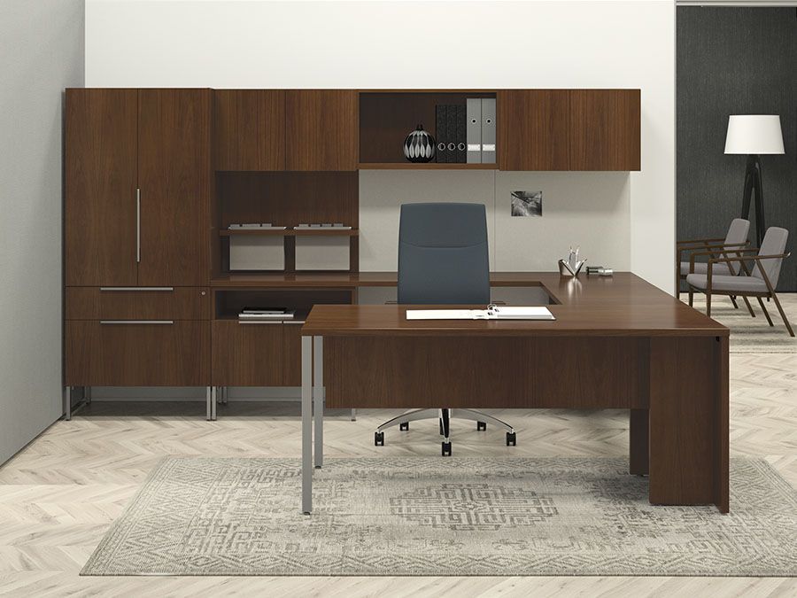Brown office desk with storage cabinets, chair, and rug in a room.