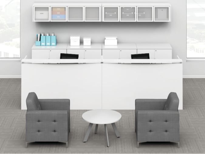 White reception desk with seating area; gray armchairs, white table, and cabinets.