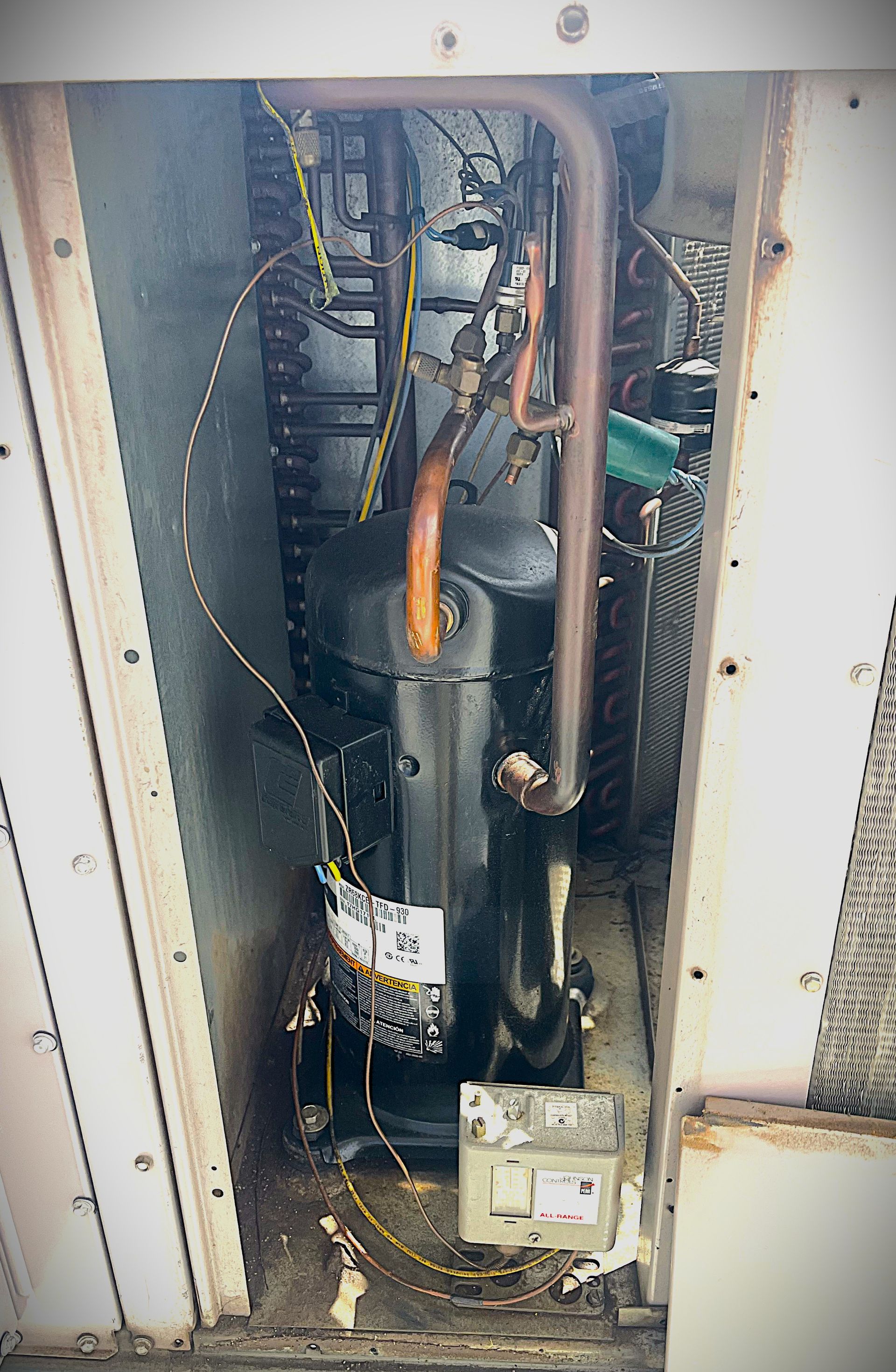 Worker inspecting electrical control panel with wires and gauges in a utility room