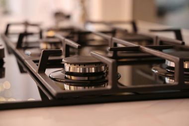 Close-up of a black gas stovetop with metal burners and knobs in a kitchen