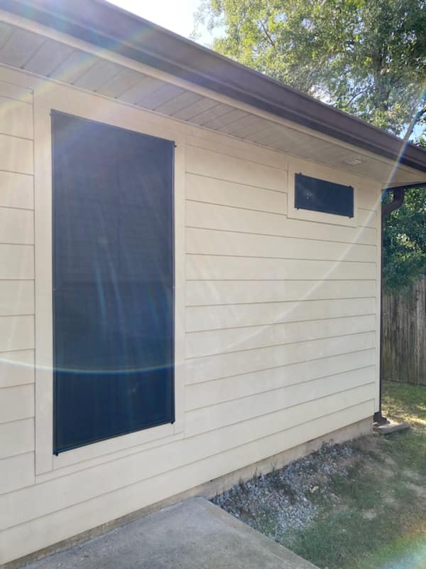 Tan building exterior with two black rectangle windows and brown gutters.