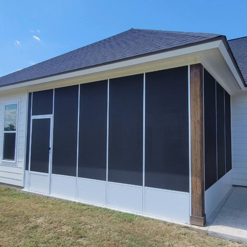 Screened porch attached to a white house with a dark roof. Black screens, white frames, and a door are visible.