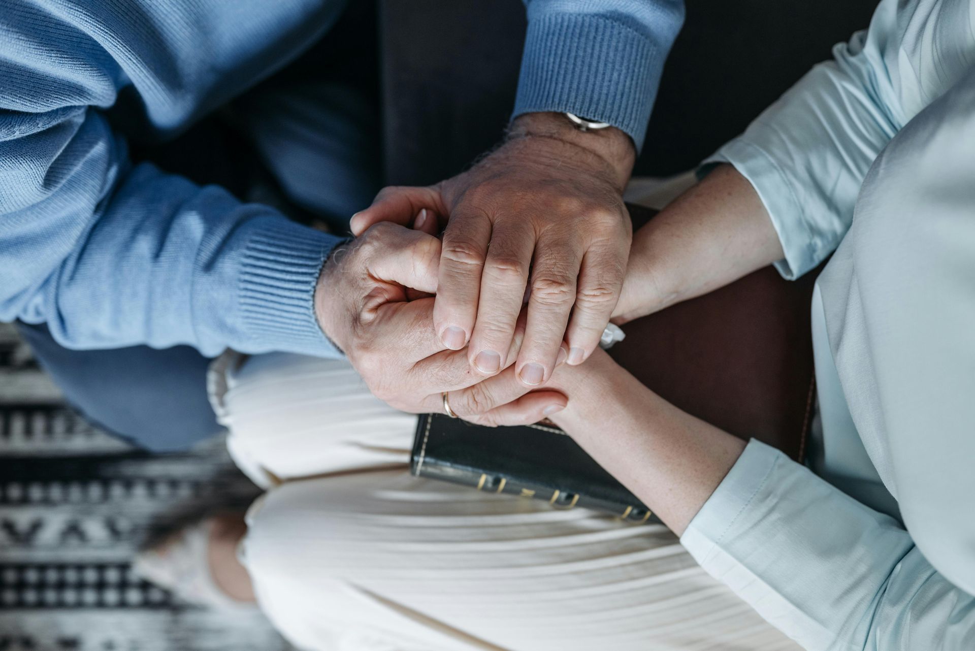 Four hands stacked together over a notebook in a supportive team meeting