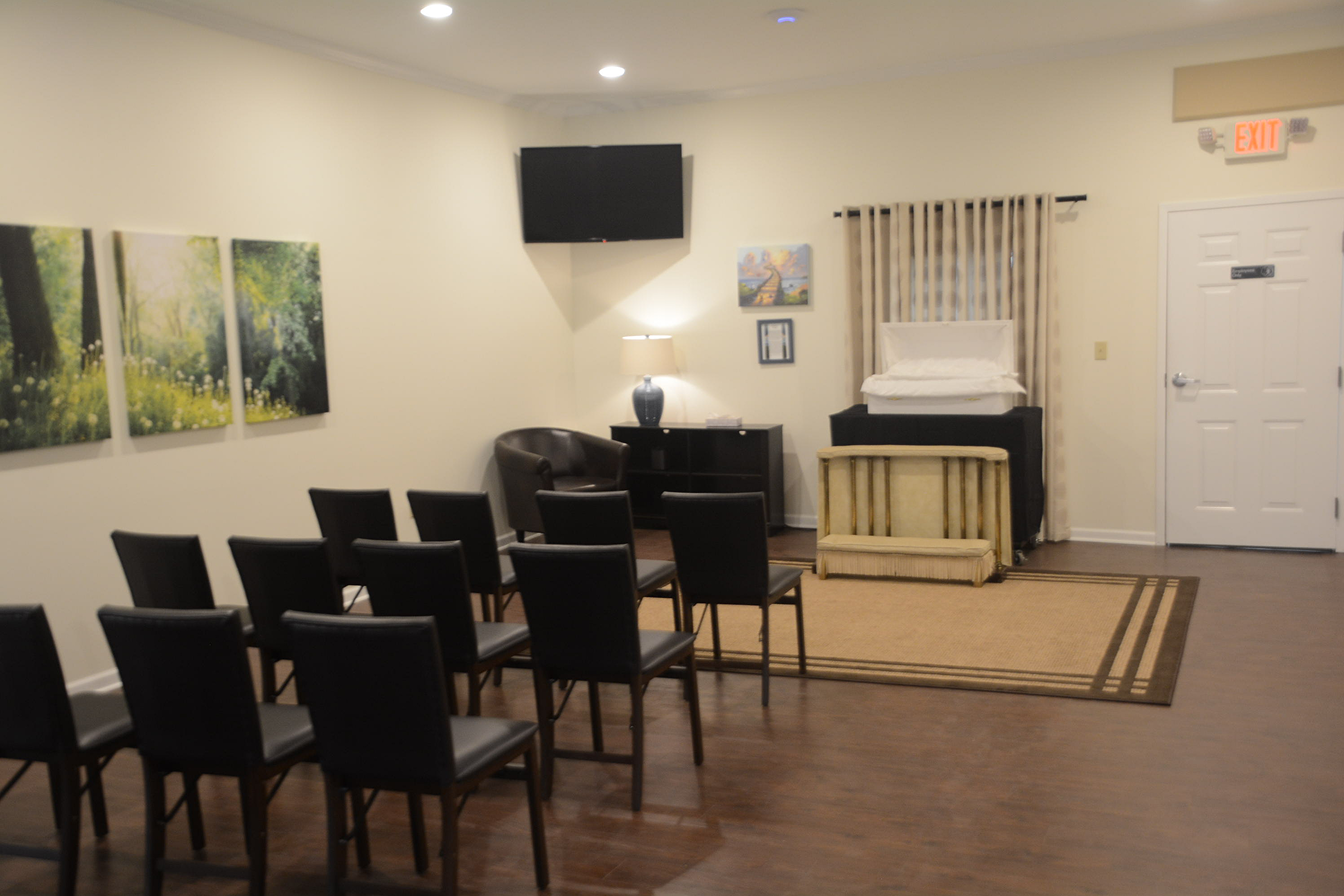 Waiting room with black chairs, wall art, and a TV in a beige office lobby