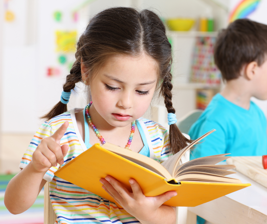 A little girl is reading a book in a classroom