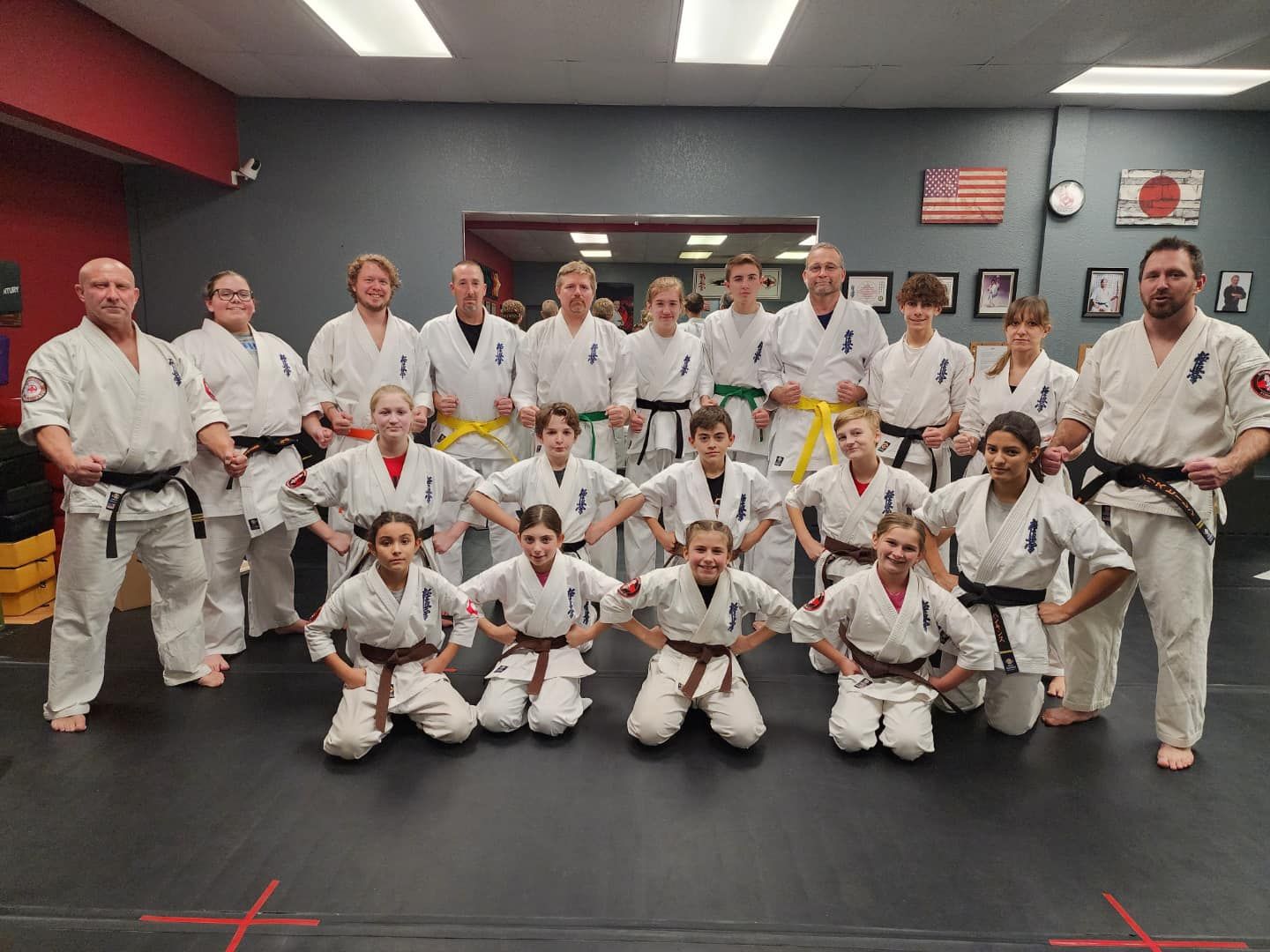 A group of people in karate uniforms are posing for a picture in a gym.
