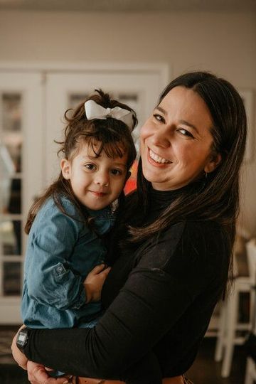 A woman is holding a little girl in her arms and smiling.