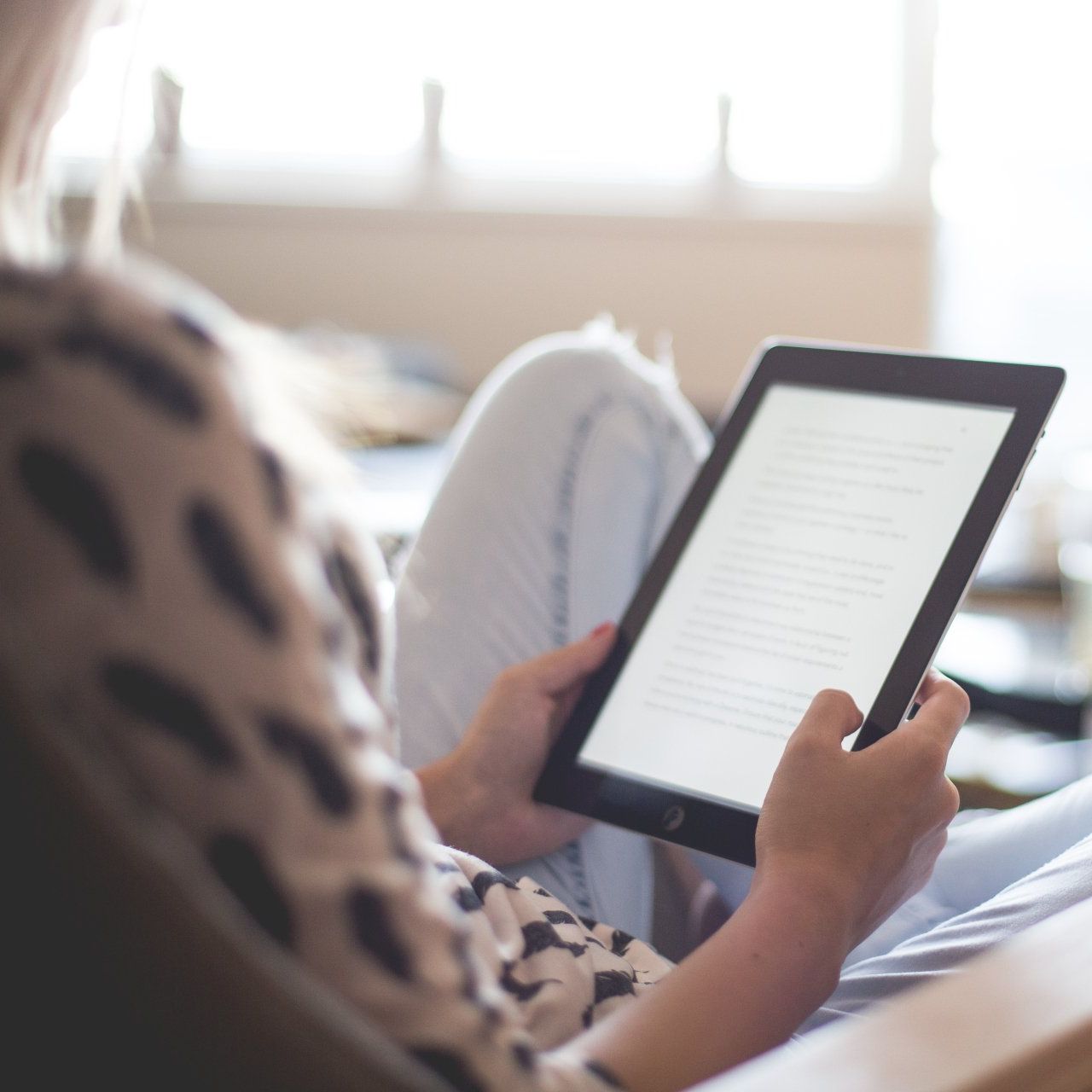 A new mother is sitting on a couch using a tablet to get help