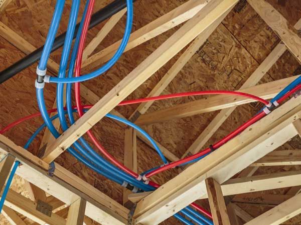 A bunch of pipes are hanging from the ceiling of a house under construction.