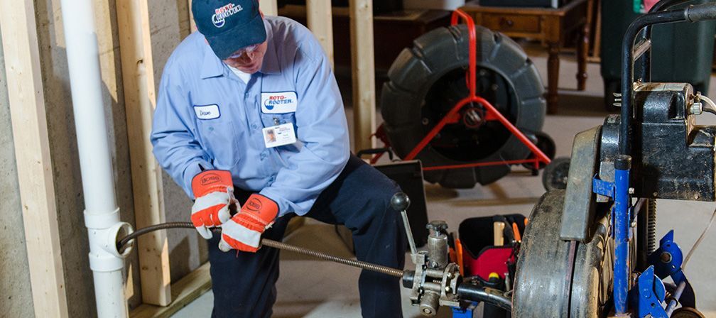 A plumber is working on a drain in a basement.