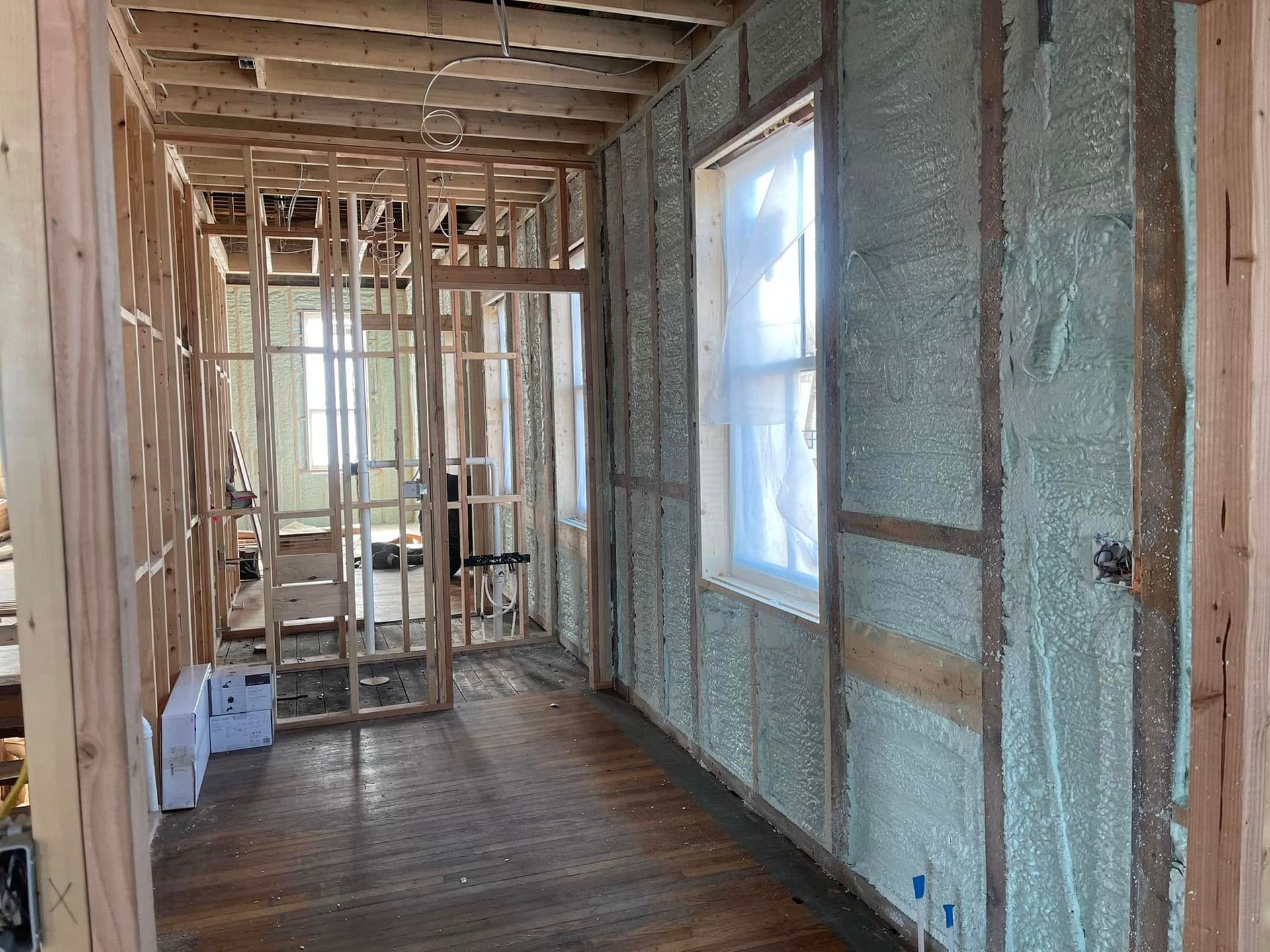 Renovation in progress: unfinished hallway with exposed studs, insulation, and a window on the right.