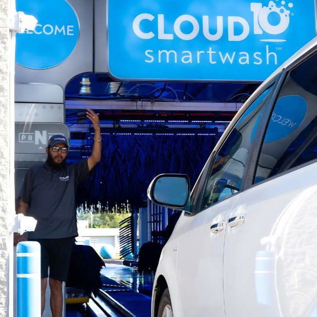 Car covered in blue foam at an automated car wash, lit by purple and blue lights