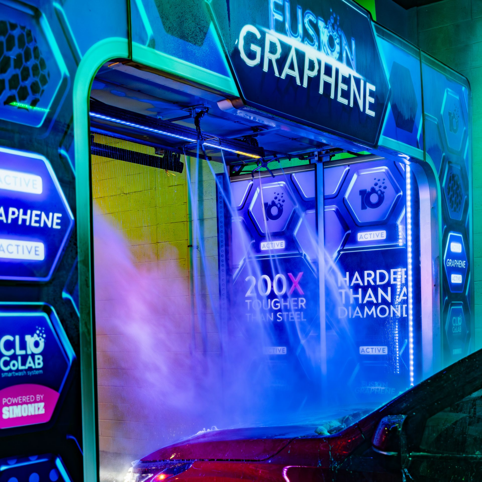 Car covered in blue foam at an automated car wash, lit by purple and blue lights