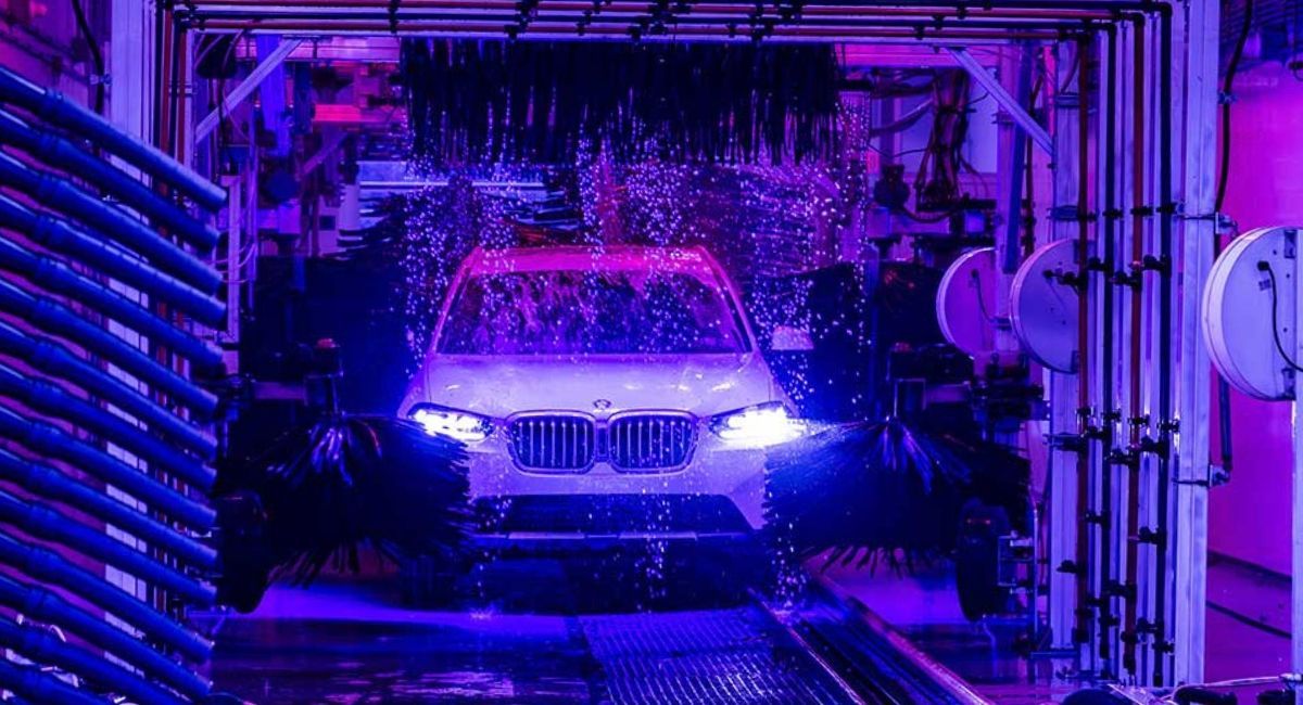 Car in a purple-lit tunnel with water spraying over it, like an automated car wash