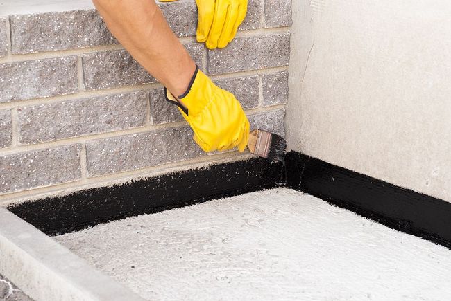 a person in yellow gloves and yellow gloves is working on a brick wall