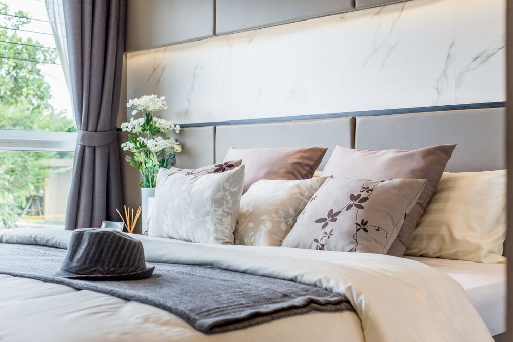 Bedroom With Bed, Pillows, Gray Throw, Hat, and Window With Curtains — Red Door Decor In Dubbo, NSW