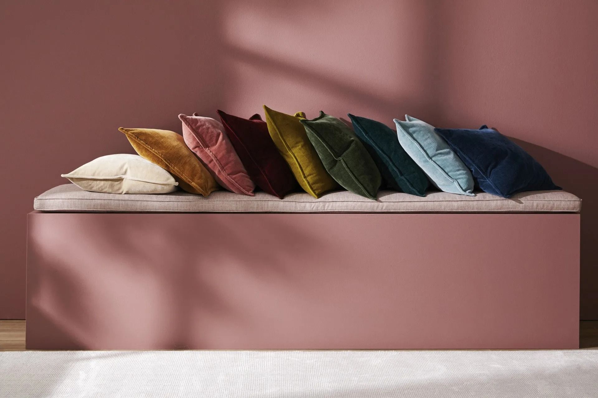 Row of Colorful Velvet Pillows on a Pink Bench Against a Matching Wall — Red Door Decor In Dubbo, NSW