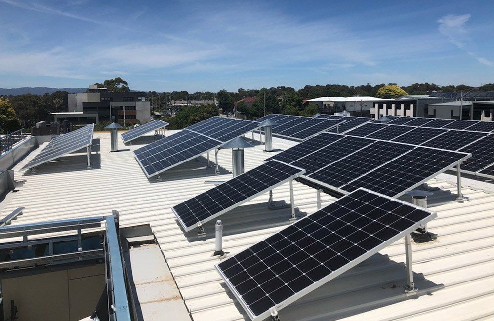 Solar panels mounted on a white rooftop under a clear blue sky