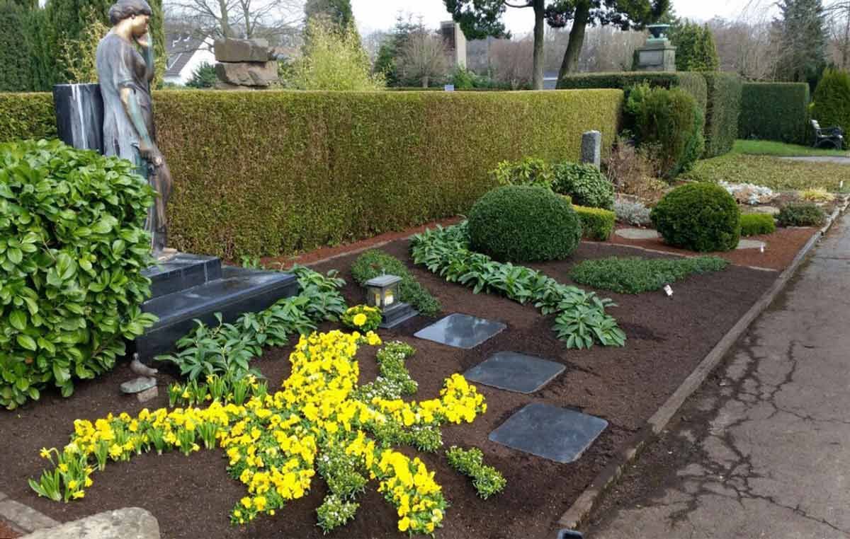 Ein Friedhof mit gelben Blumen und einer Statue im Hintergrund