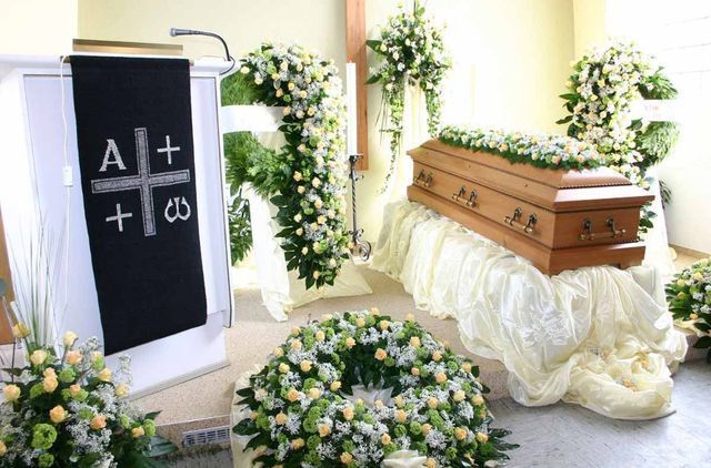 Die Erdbestattung bei Bestatter Alfred Roth in Remscheid Ein Sarg steht auf einem Tisch in einer Kirche, umgeben von Blumen - eine Erdbestattung.