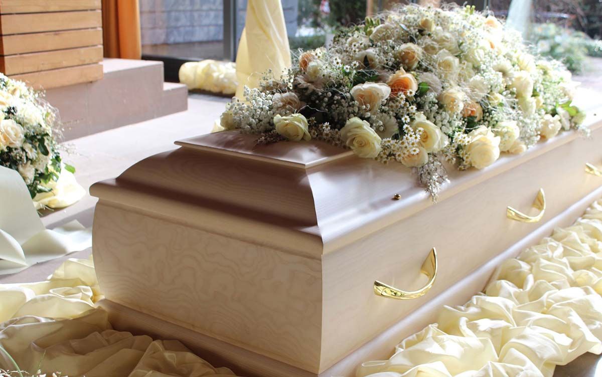 Auf einem Tisch steht ein Sarg mit Blumen darauf.