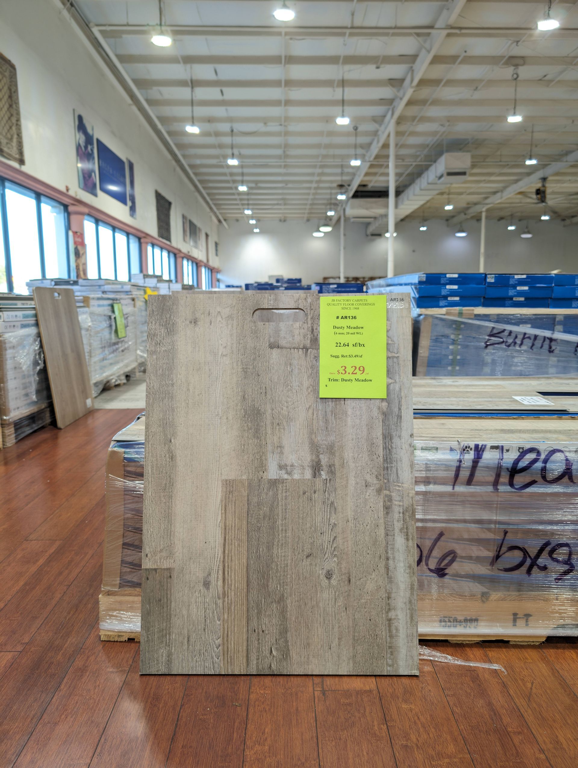 A sample of wood-look flooring with a price tag, in a warehouse setting.