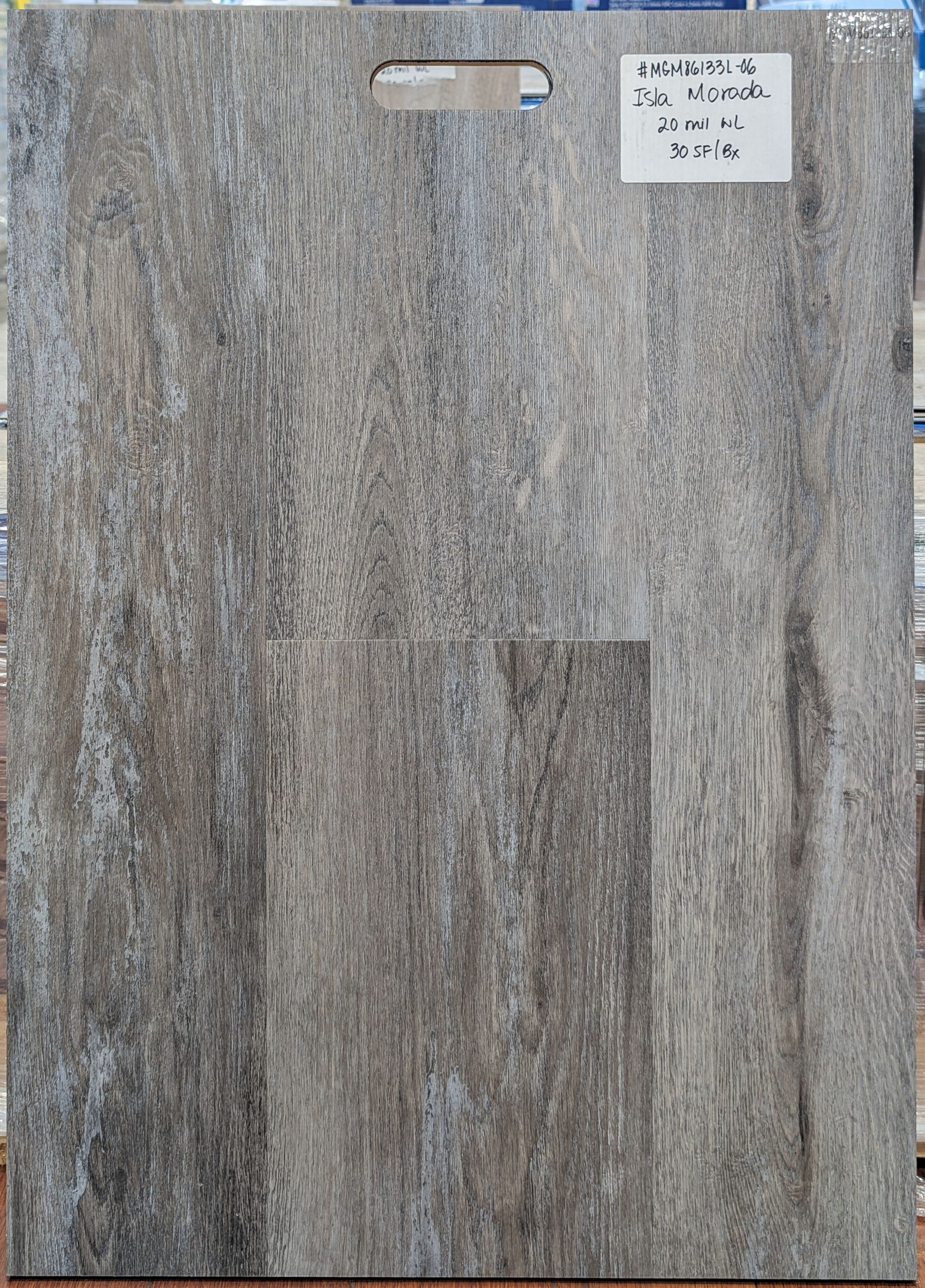 Gray wood-look flooring sample with a notched handle and a white product label.