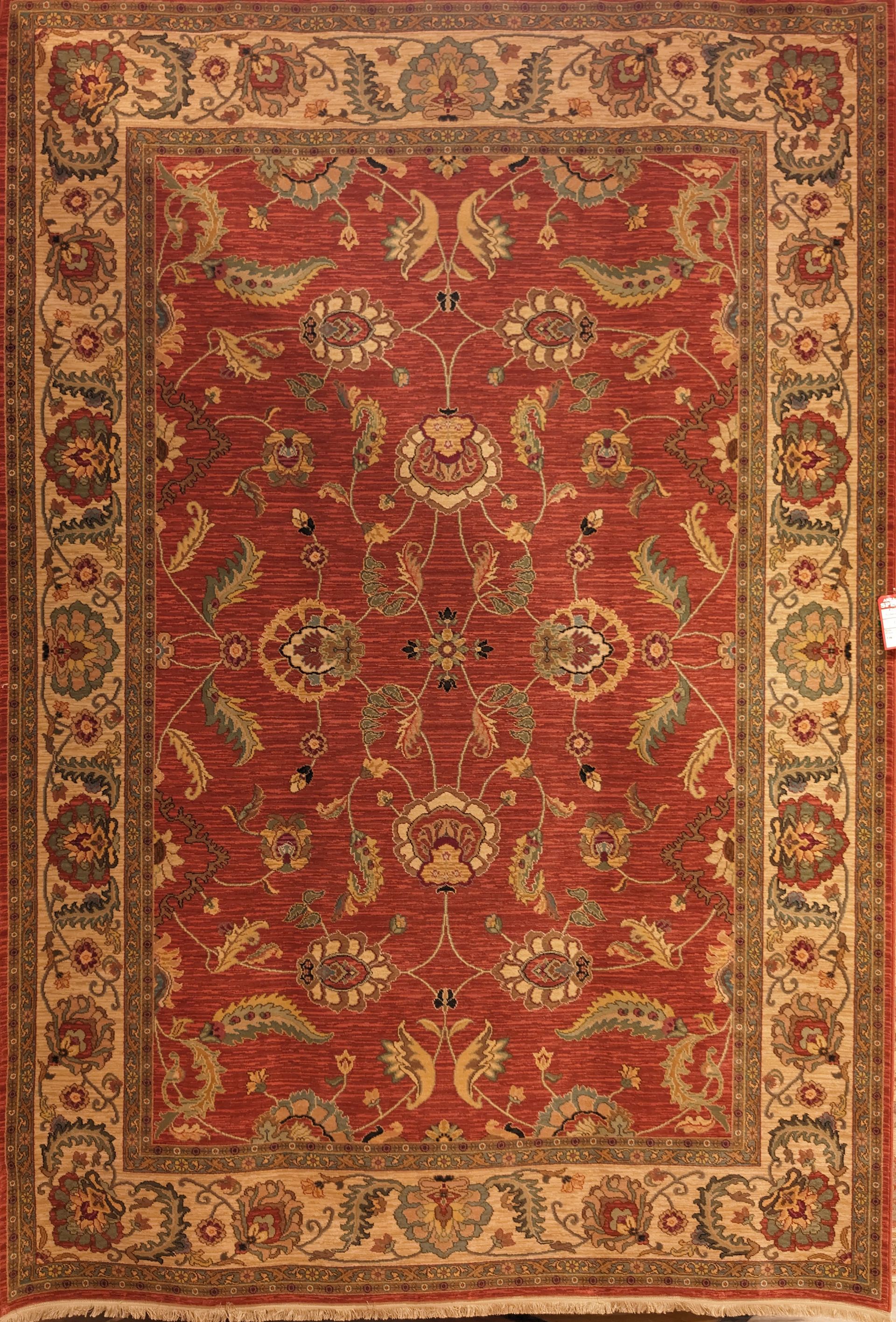 Red patterned oriental rug with ornate floral border on a beige background