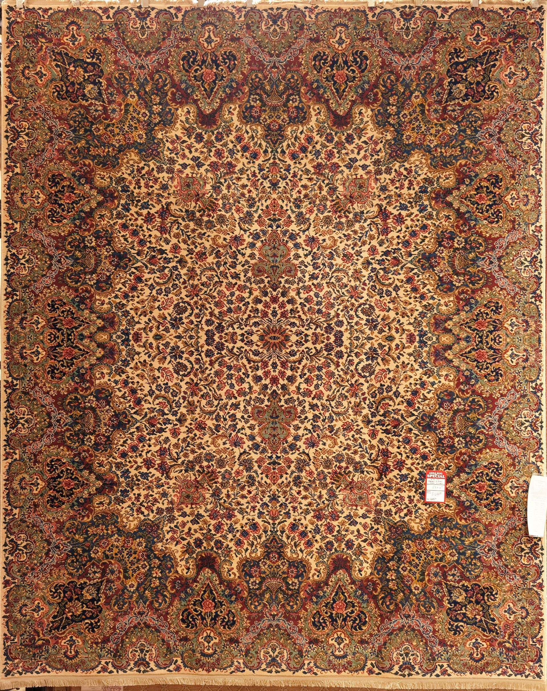 Ornate vintage floral rug in red, gold, and brown tones with a small white label on the right edge