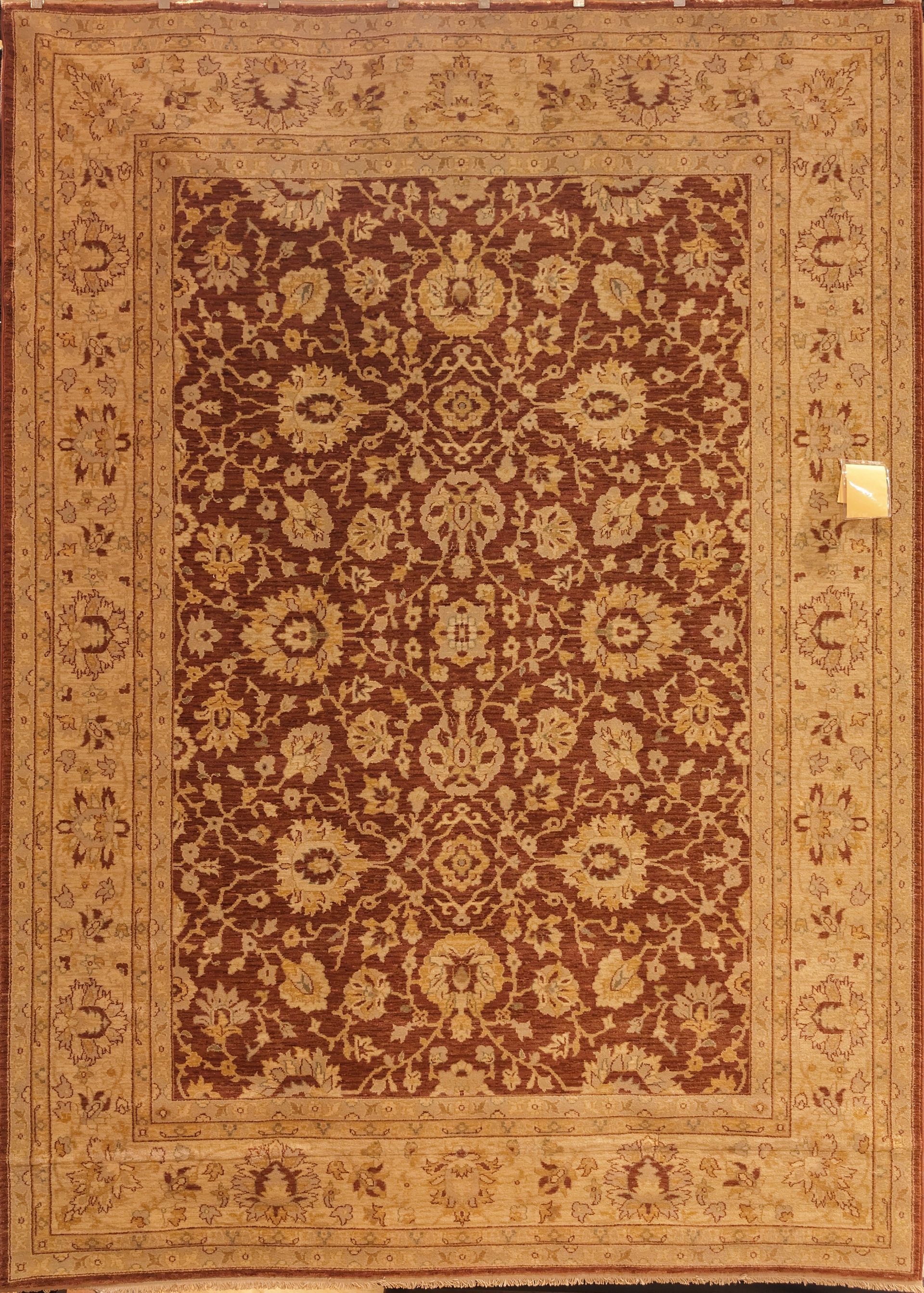 Antique beige rug with a red floral pattern and ornate border centered on a plain background