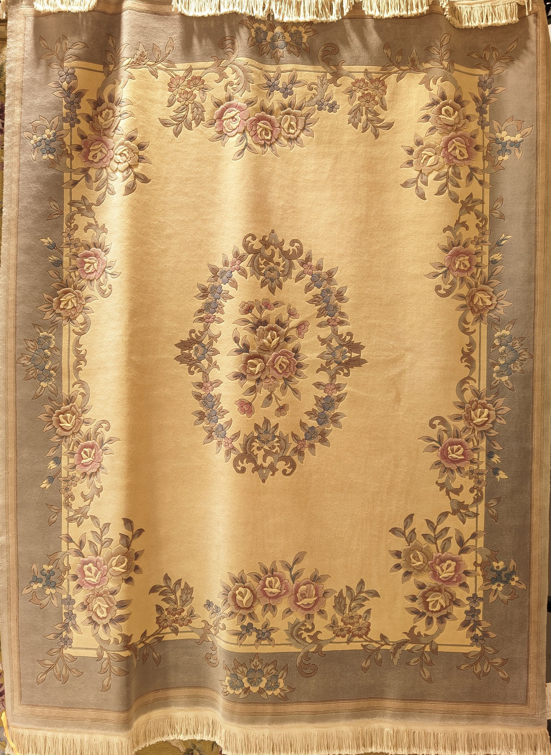 Beige floral patterned tapestry or curtain with a central oval wreath design and ornate border