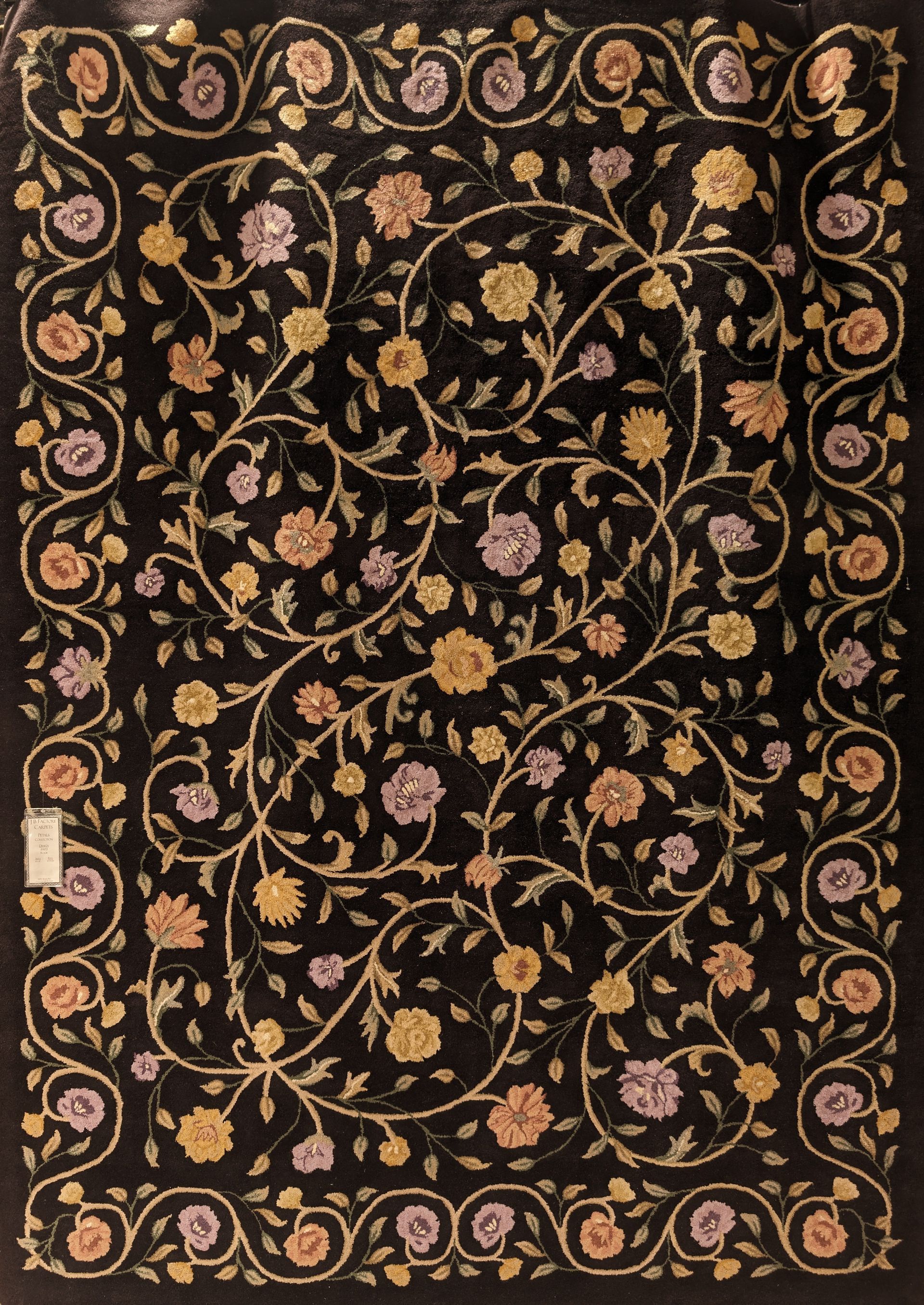 Ornate black floral textile with gold and pink vine patterns and a decorative border
